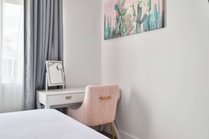 A bedroom with a bed, a desk with a mirror, a chair, and a wall art piece. - Luxe Home 4B3B with Heated Pool/Jacuzzi & Parking (Scottsdale)