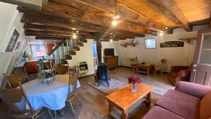 Un acogedor espacio tipo loft con comedor, un sofá y una escalera que sube a un nivel superior.