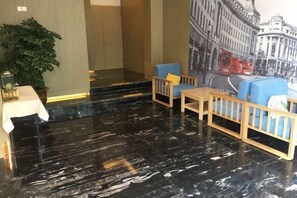 A lobby with a black marble floor, wooden furniture, a table with a lamp, and a large cityscape mural on the wall. - Waiting Qingju Hotel (Shanghai New International Expo Center） (Shanghai)