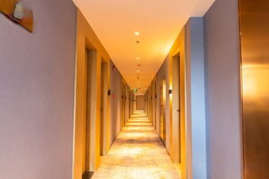 A hotel corridor with doors on both sides, a carpeted floor, and overhead lighting. - Waiting Qingju Hotel (Shanghai New International Expo Center） (Shanghai)