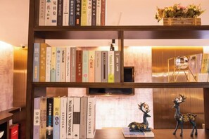 A bookshelf with books and decorative items, including a small deer figurine. - Waiting Qingju Hotel (Shanghai New International Expo Center） (Shanghai)