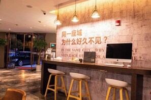 A reception desk with a computer monitor, a phone, and a menu board. There are three stools in front of the desk. - Waiting Qingju Hotel (Shanghai New International Expo Center） (Shanghai)