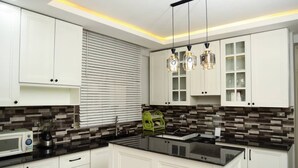 Una cocina moderna con armarios blancos, encimera negra y salpicadero con un diseño de mosaico.