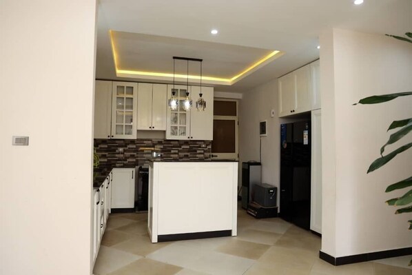 Una cocina moderna con armarios blancos, una isla central e iluminación colgante.