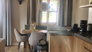 Eine moderne Küche mit Holzausstattung, einem Essbereich mit zwei Stühlen, einem Deckenventilator und einem Fenster mit Vorhängen.