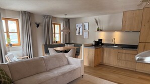 Ein modernes Wohnzimmer mit Sofa, Esstisch und Küchenbereich, ausgestattet mit Holdekor-Schränken und einer Arbeitsplatte.