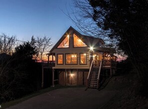 A two-story log cabin with a balcony and a staircase leading to the upper level.