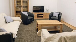 A living room with two black leather armchairs, a white sofa, a wooden coffee table, and a TV on a wooden stand. - Cozy Trogir Apartment With 3 Bedrooms (Trogir)