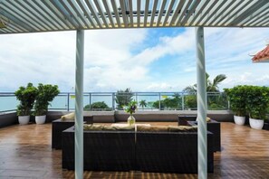 A rooftop terrace with a covered seating area, potted plants, and a view of the sea. - Seabreeze Inn (Shenzhen)