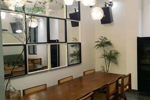 A dining area with a wooden table, chairs, a large mirror, and a hanging light fixture. - Seabreeze Inn (Shenzhen)