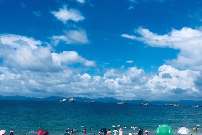 A beach with people, boats, and a clear sky.