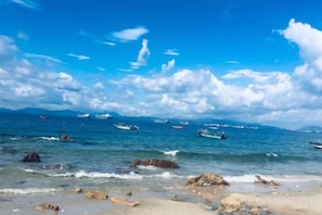 A beach with clear skies, calm waters, and boats in the distance. - Seabreeze Inn (Shenzhen)