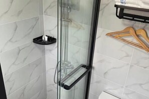 Bathroom features a glass-enclosed shower and a wall-mounted shelf.