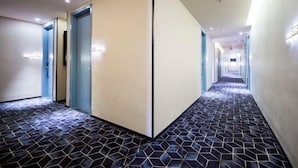 A hotel corridor with a geometric patterned floor, a central divider, and doors on both sides. - 100 Inn Hotel (Shanghai Zhenping Road Subway Station) (Shanghai)