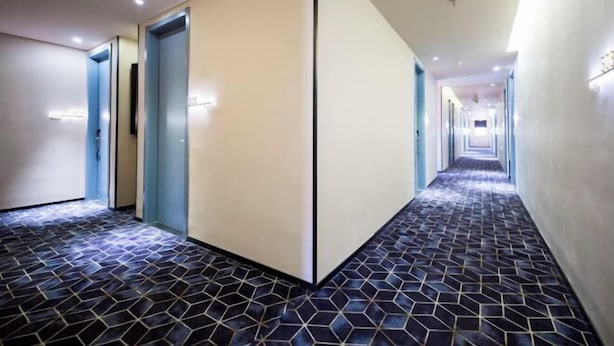 A hotel corridor with a geometric patterned floor, a central divider, and doors on both sides. - 100 Inn Hotel (Shanghai Zhenping Road Subway Station) (Shanghai)