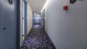 A hotel hallway with a patterned floor, doors, and a fire alarm on the wall. - 100 Inn Hotel (Shanghai Zhenping Road Subway Station) (Shanghai)