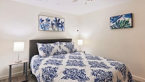 Ein Schlafzimmer mit Bett, zwei Nachttischen und Deckenventilator.