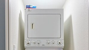 Ein kleiner, weißer Hauswirtschaftsraum mit Waschmaschine und Trockner, einem Mopp und einer Flasche Reinigungsmittel darauf.