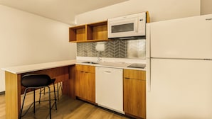 A compact kitchen with a microwave, dishwasher, and a small bar stool. - LivAway Suites Seattle-Renton (Renton)