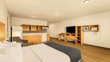 Une chambre d’hôtel équipée d’un lit, d’un bureau, d’une chaise, d’une kitchenette et d’une télévision.