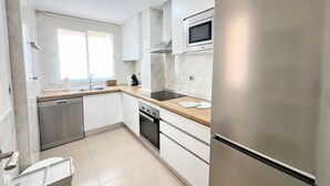 Una cocina moderna con armarios blancos, electrodomésticos de acero inoxidable y encimera de madera.