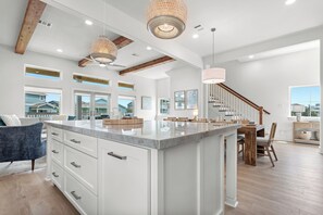 A spacious kitchen with a large island, wooden beams, and pendant lighting. - Stunning New Beach House in Pointe West, Galveston.  Amazing Gulf Coast Views! (Galveston)