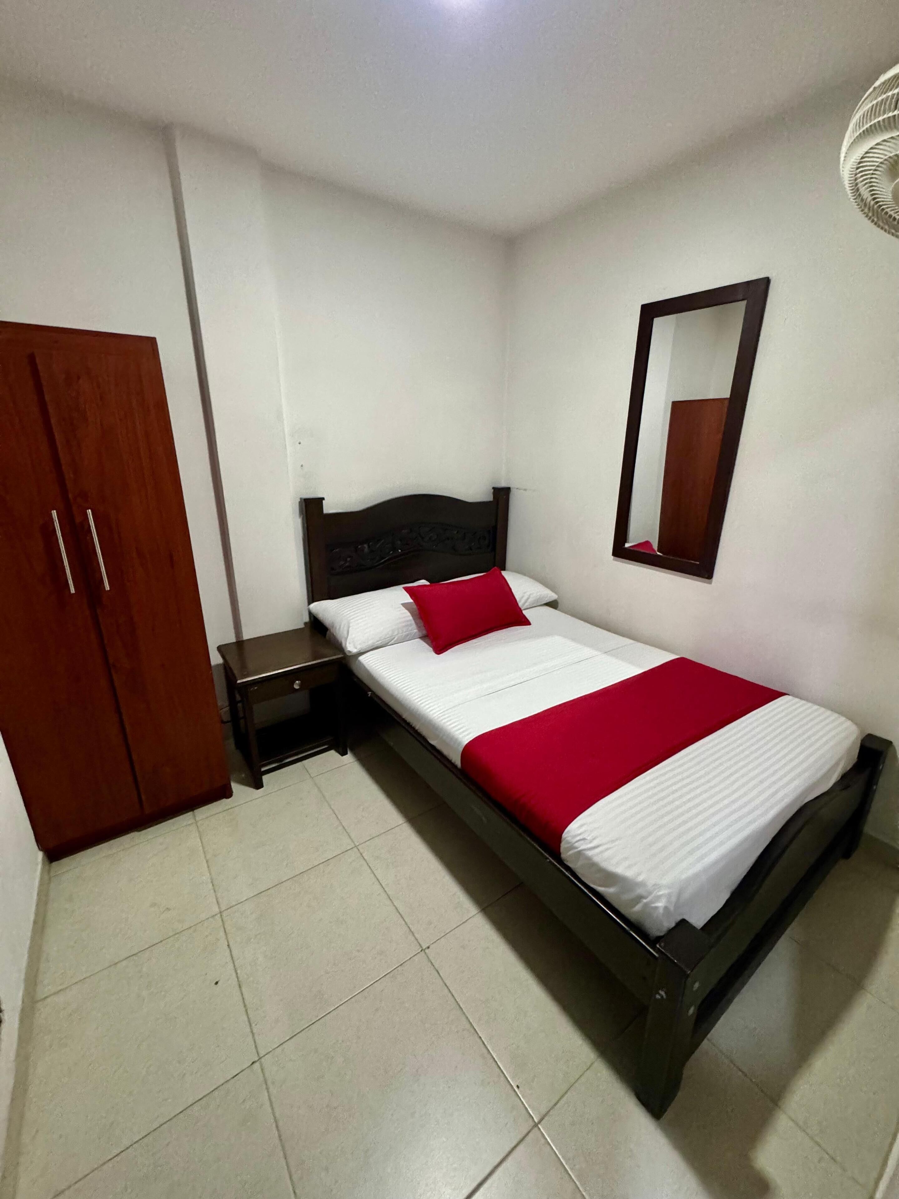 Un dormitorio con cama, armario, mesita de noche y espejo.