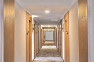 Un largo pasillo estrecho con puertas a ambos lados, que conduce a habitaciones individuales.