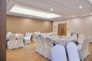 A conference room with round tables, white chairs, and a wooden floor. - Celebrity Youngsun Xinhua Hotel (Mianyang)