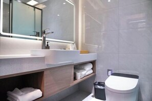 A modern bathroom with a large mirror, a sink, and a toilet. - Celebrity Youngsun Xinhua Hotel (Mianyang)