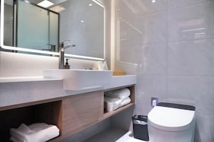 Un baño moderno con un espejo grande, un lavamanos y un inodoro.