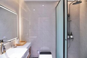 A modern bathroom with a glass shower enclosure, a white sink, and a mirror. - Celebrity Youngsun Xinhua Hotel (Mianyang)
