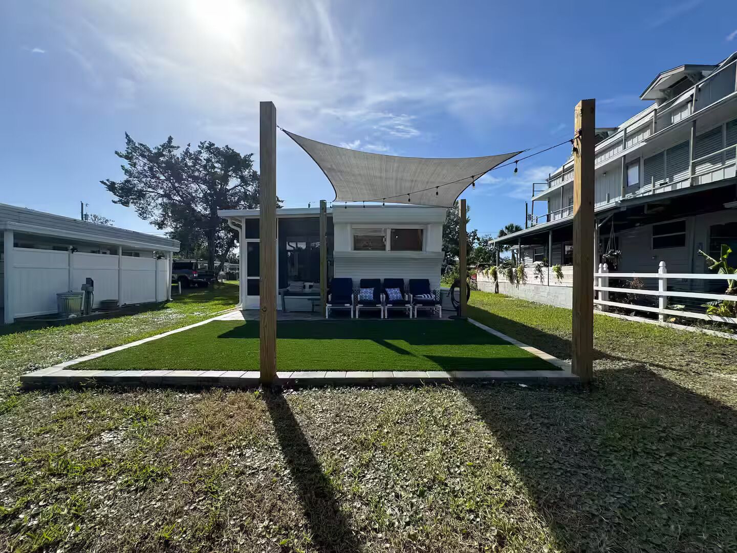 A modern outdoor seating area with a white building, a grassy lawn, and a white fence.