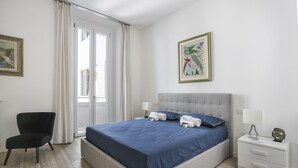 A bedroom with a bed, a chair, a nightstand, and a painting on the wall. - Modern Comfort in Florence (Firenze)