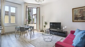 A modern living room with a dining area, a TV, and a painting on the wall. - Modern Comfort in Florence (Firenze)