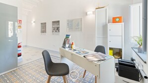 A modern office space with a desk, chairs, and a printer. There are framed pictures on the wall, a map, and a small cabinet with a plant. - Rosa dei Venti - Room Maestrale (Cabras)
