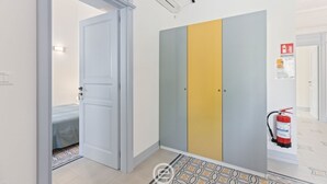 Un couloir avec un lit, une armoire et un extincteur.