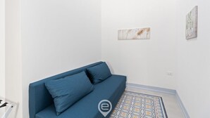 Une pièce avec un canapé bleu, un sol à motifs et deux œuvres d’art accrochées au mur.
