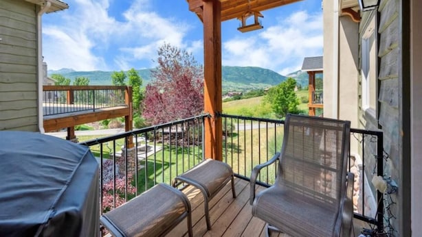 A covered porch with two chairs and a table, overlooking a scenic landscape with mountains and trees. - Eden Basecamp | w/Pool, Hot Tub, + Sauna (Eden)