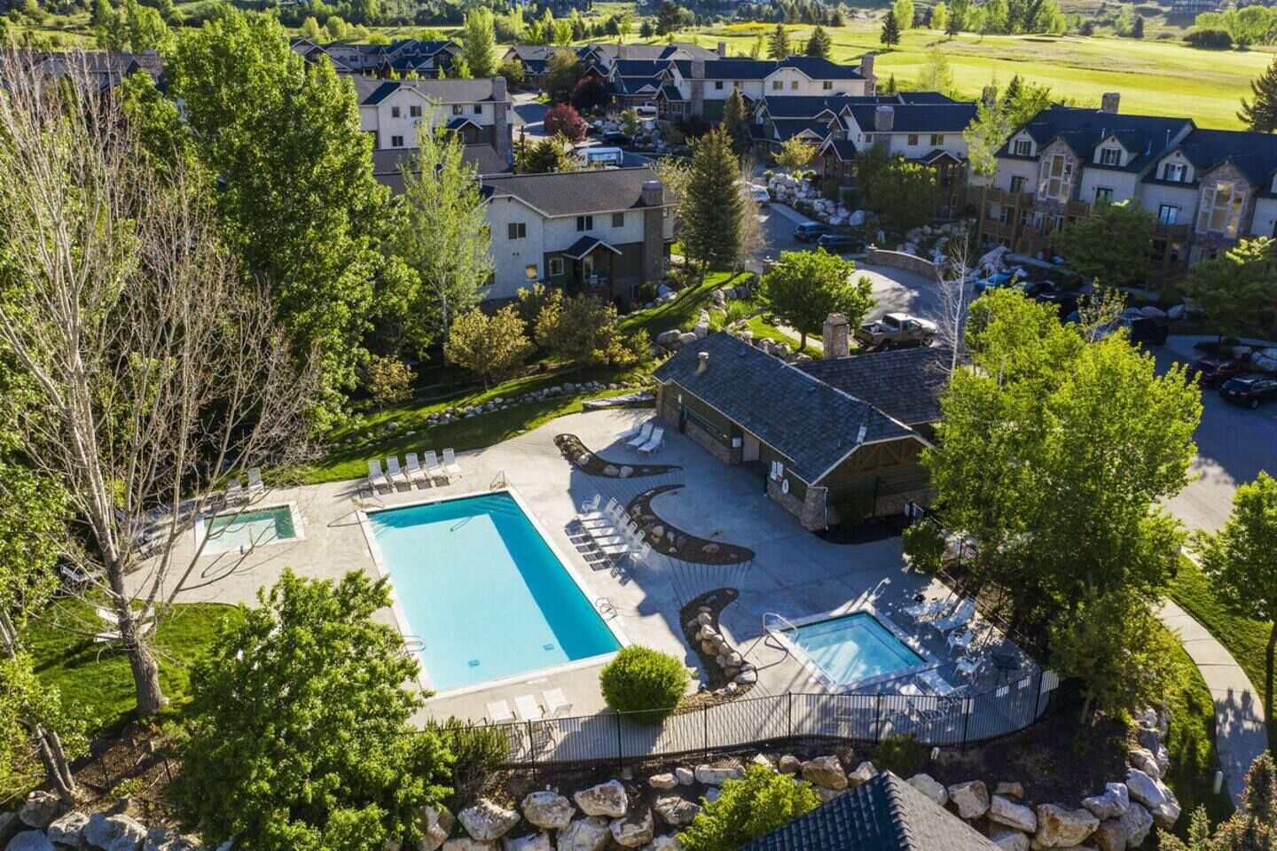 Vue aérienne d’un quartier résidentiel avec une piscine, des chaises longues et un bâtiment en pierre.
