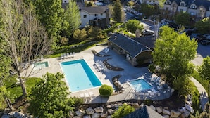 An aerial view of a residential area with a swimming pool, lounge chairs, and a stone building. - Eden Basecamp | w/Pool, Hot Tub, + Sauna (Eden)