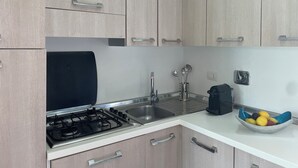 Eine moderne Küche mit hellen Holzschränken, Edelstahlgeräten und einer Fruchtschale auf der Arbeitsfläche.