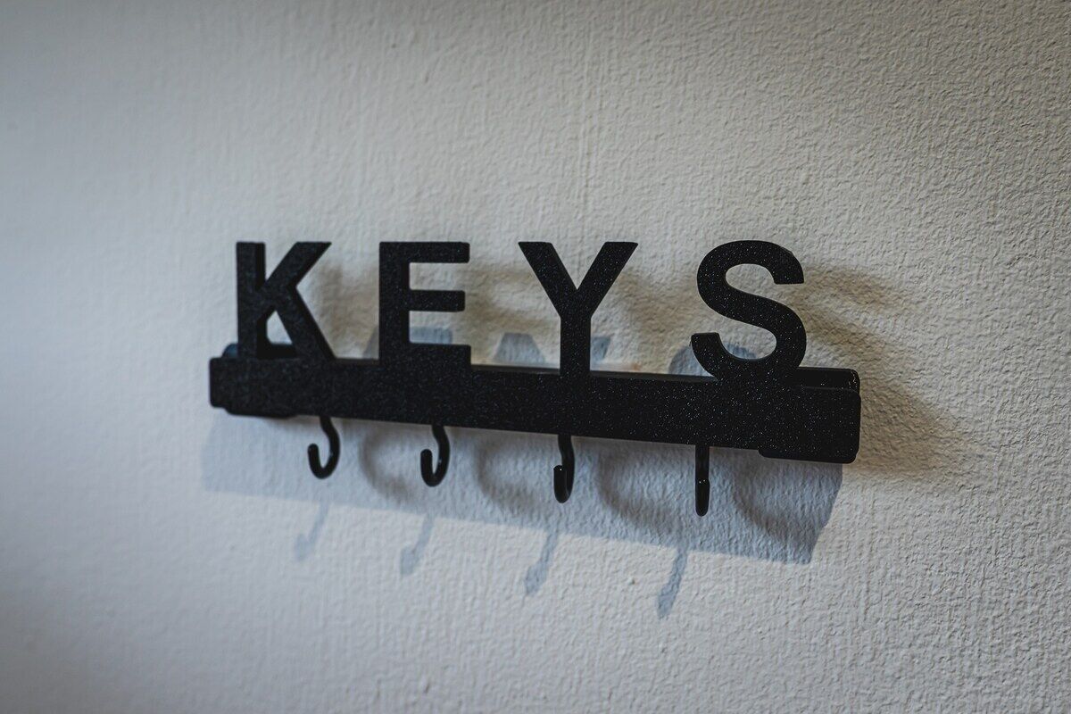 A black metal wall-mounted rack with the word "KEYS" and hooks for hanging keys.