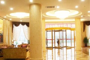 Un vestíbulo de hotel con mostrador de recepción, zona de estar y un pilar grande.