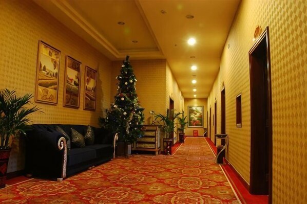 Corredor de hotel com tapete vermelho, árvore de Natal e um sofá.