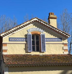 A building with a sign reading "CAVALIER" above a window with shutters. - Appartement avec jardin - Cavalière (Le Lavandou)