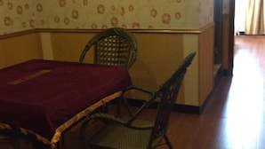 A room with a dining table, a wicker chair, and a patterned wallpaper. - Jiazhou Hotel (Chongqing Yiyuan) (Chongqing)