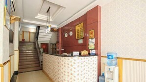 A reception area with a counter, a water dispenser, and a staircase leading to another floor. - Jiazhou Hotel (Chongqing Yiyuan) (Chongqing)