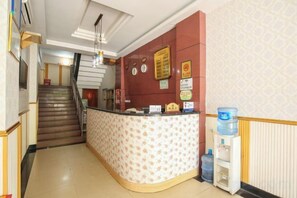 A reception area with a counter, a water dispenser, and a staircase leading to an upper floor. - Jiazhou Hotel (Chongqing Yiyuan) (Chongqing)