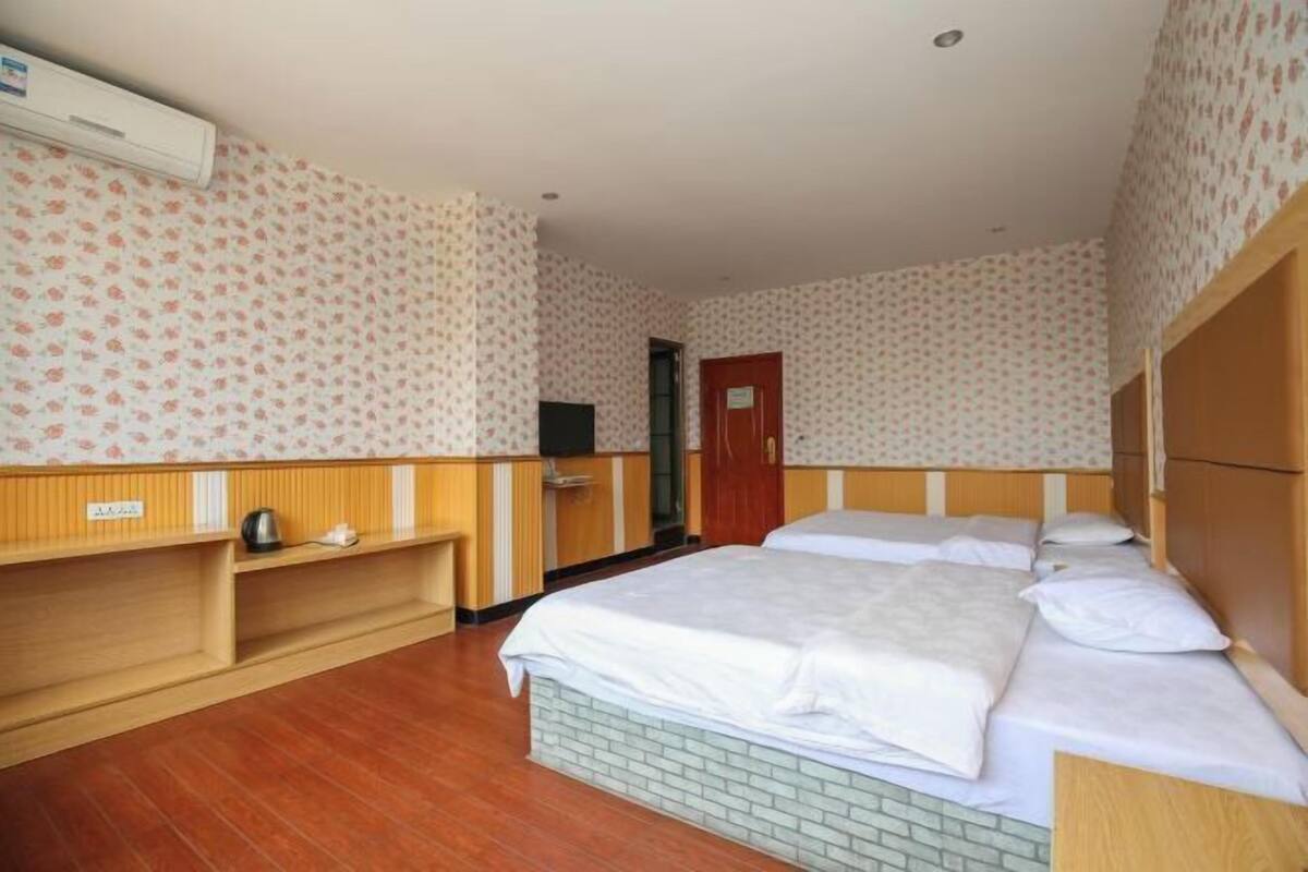 Una habitación de hotel con dos camas, un armario de madera, un escritorio pequeño y un televisor.